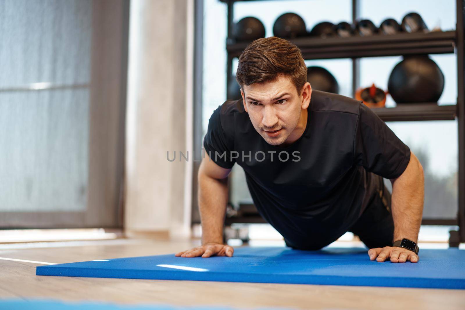 Young athletic man doing push-ups in a gym, close up photo