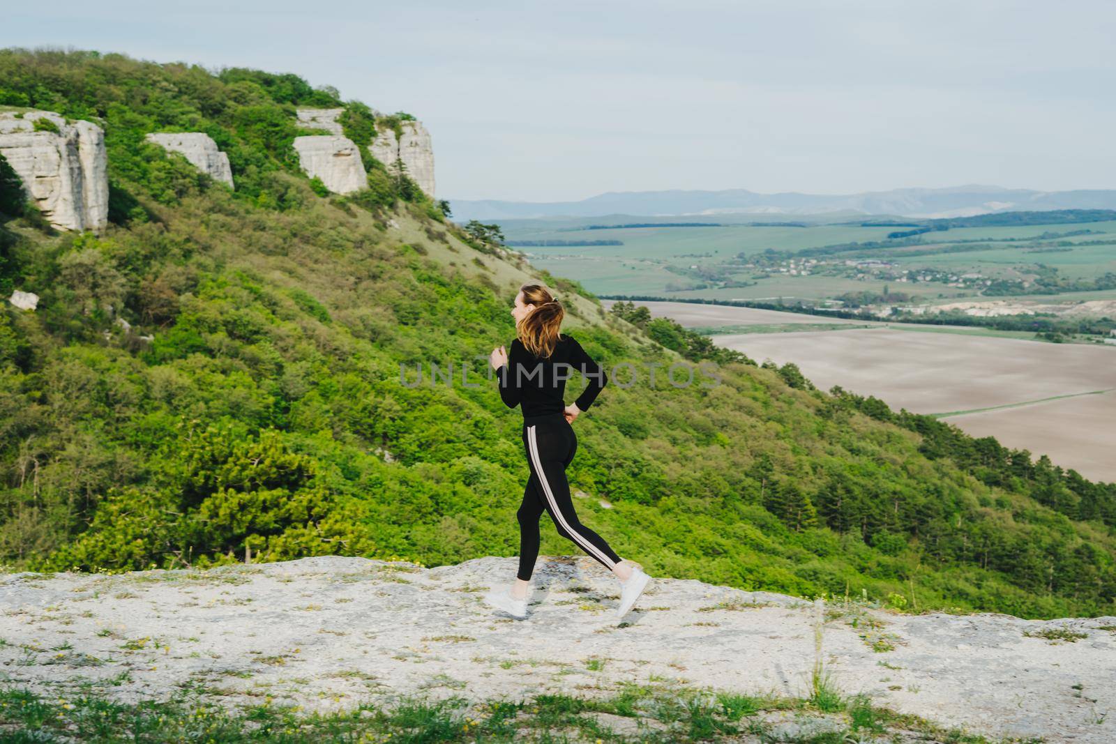 A girl runs in the mountains. Outdoor sports.