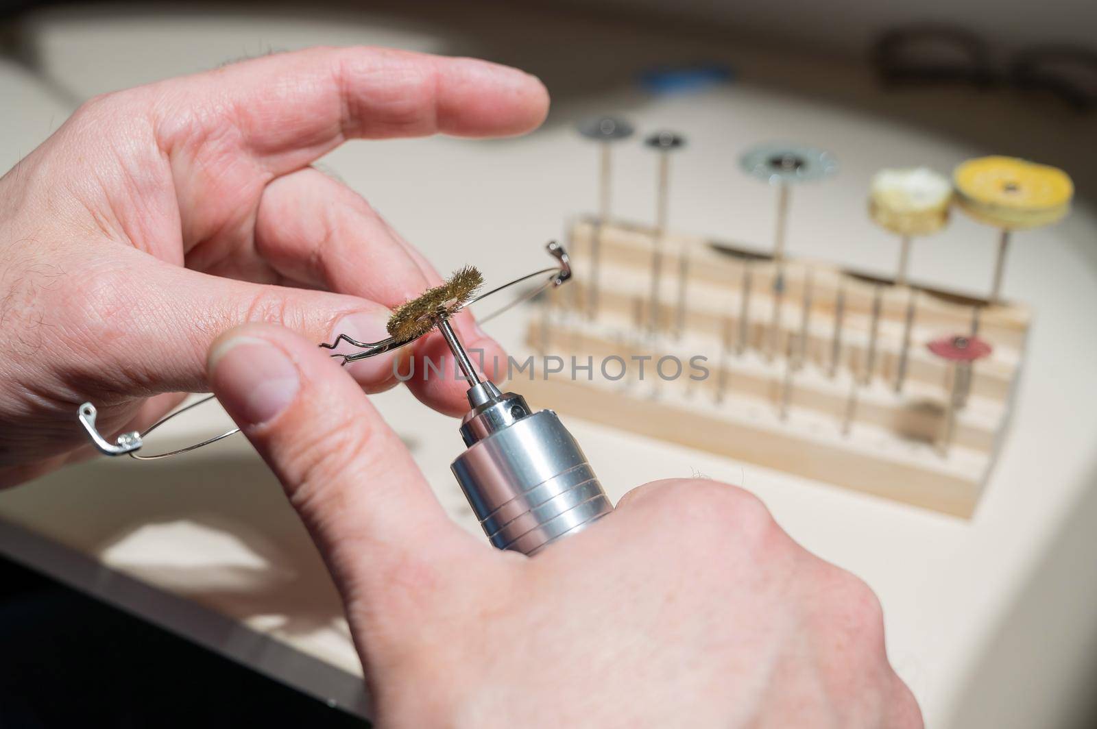 An optician technician polishes the frame of glasses. A professional optician fixes glasses