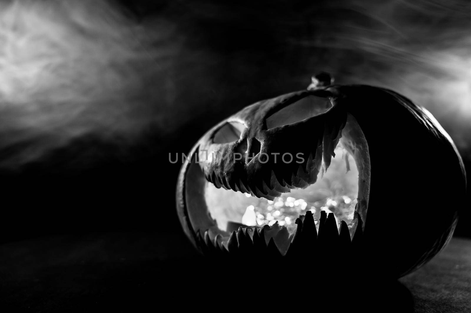 A creepy pumpkin with a carved grimace in the smoke. Jack o lantern in the dark