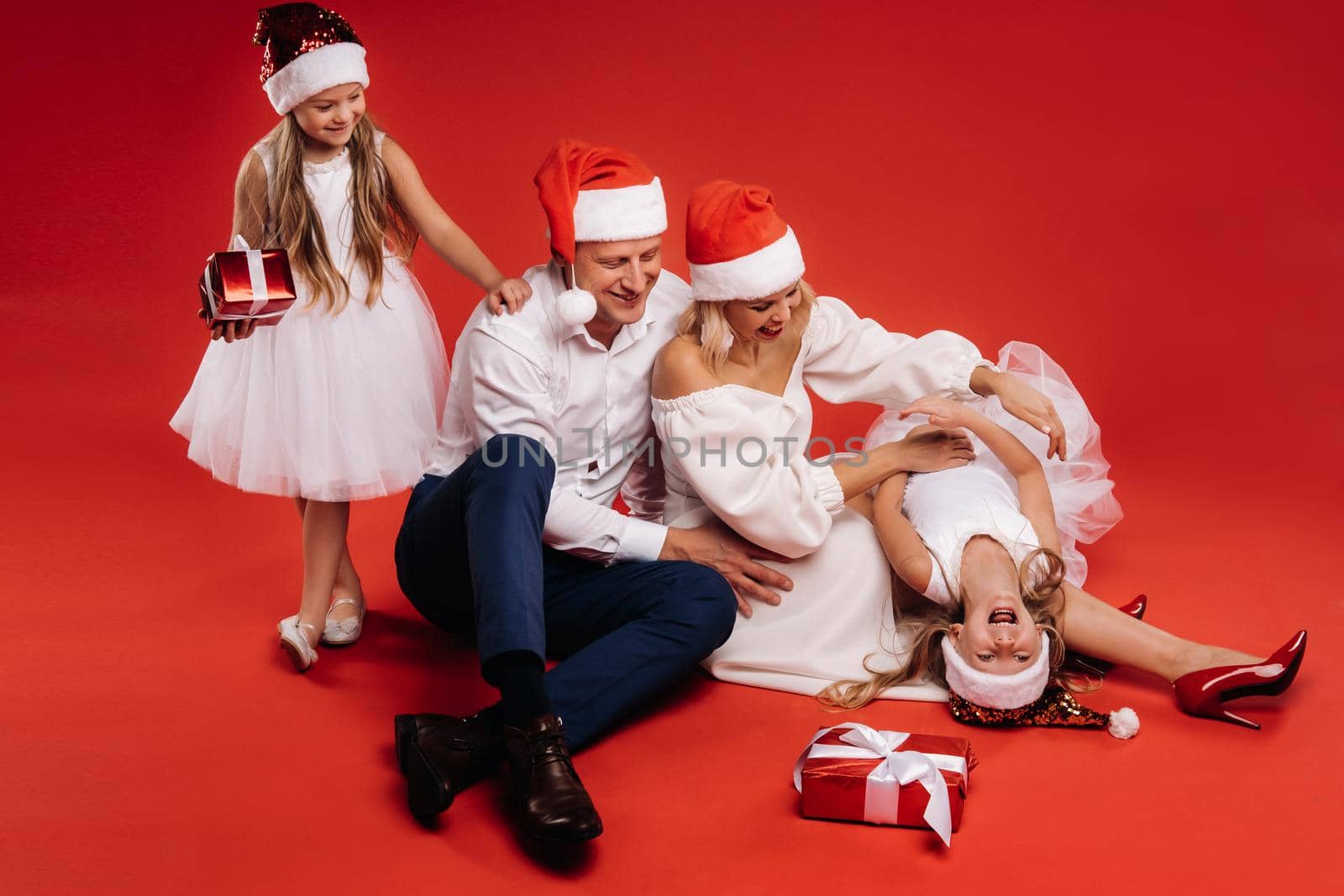 Portrait of a happy family in a Christmas hat on a red background by Lobachad
