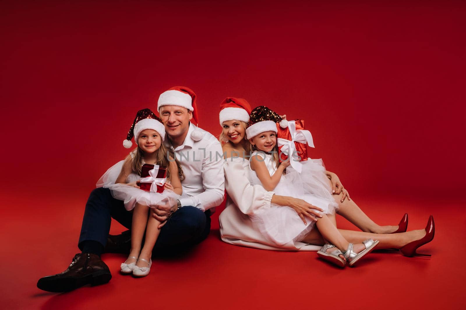 Portrait of a happy family in a Christmas hat on a red background.