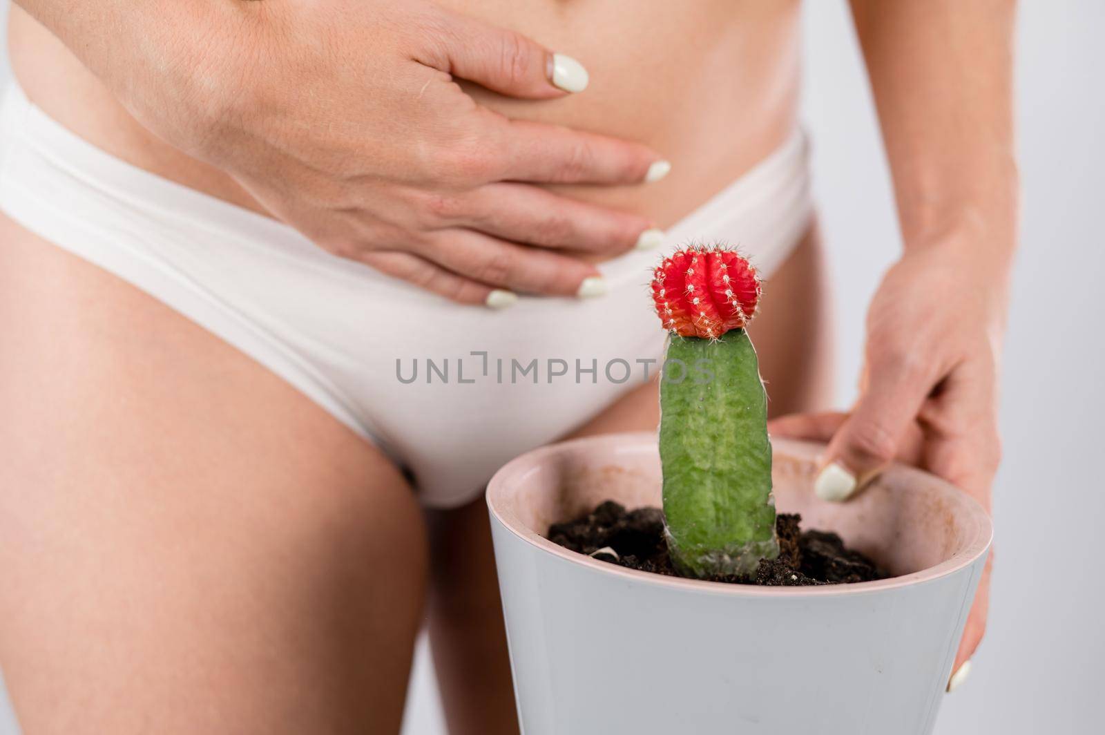 Woman in white panties holds a cactus with hand on her stomach. by mrwed54