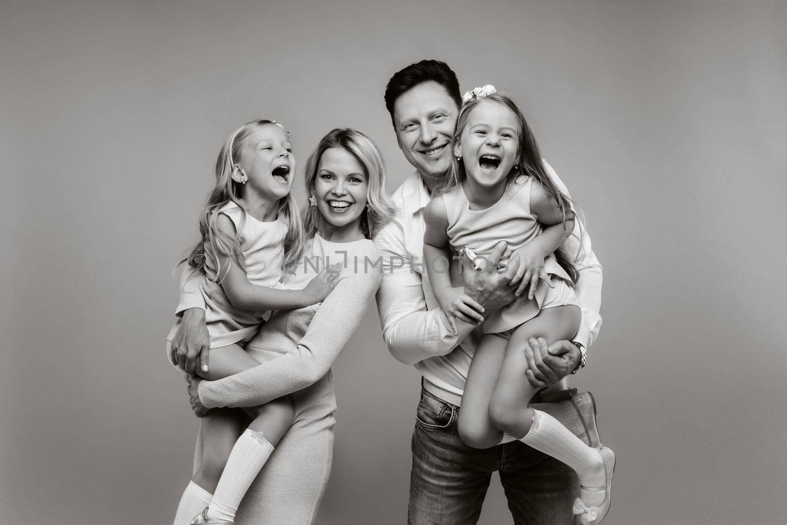 Happy parents hold their children in their arms and smile on a yellow background. an emotional family of four.