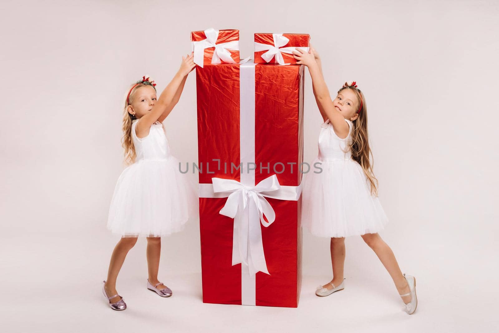 two little girls with Christmas gifts on a white background and a huge gift by Lobachad