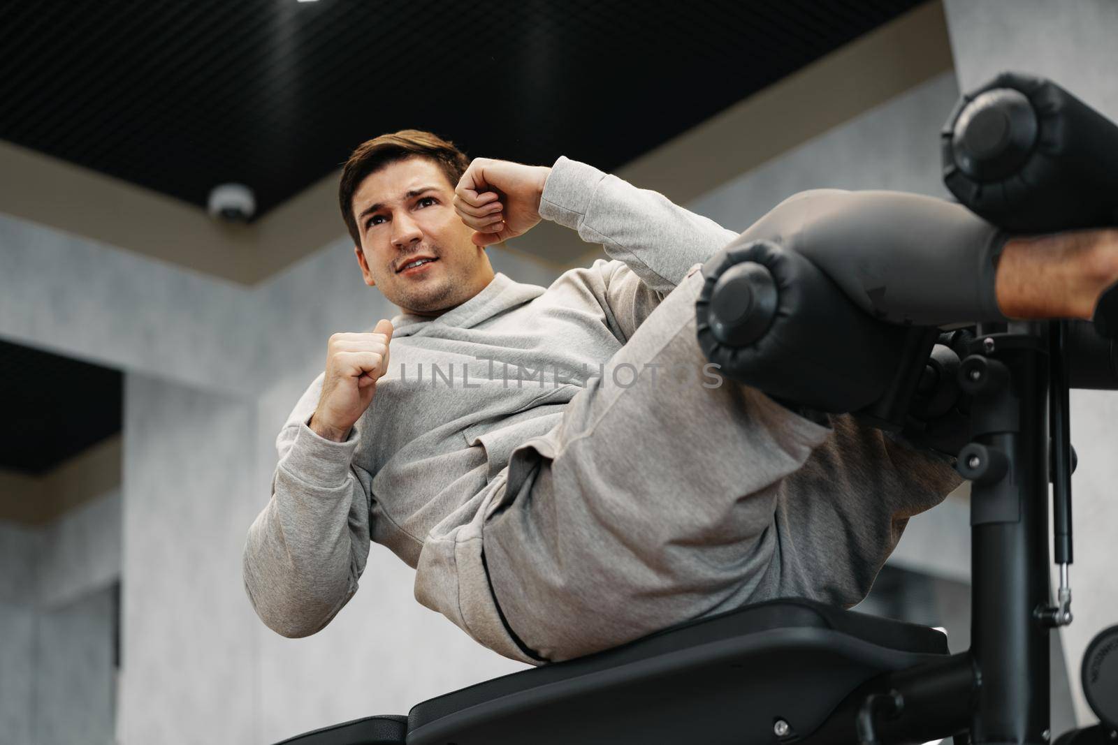 Young athlete doing abs exercises workout in modern gym, close up
