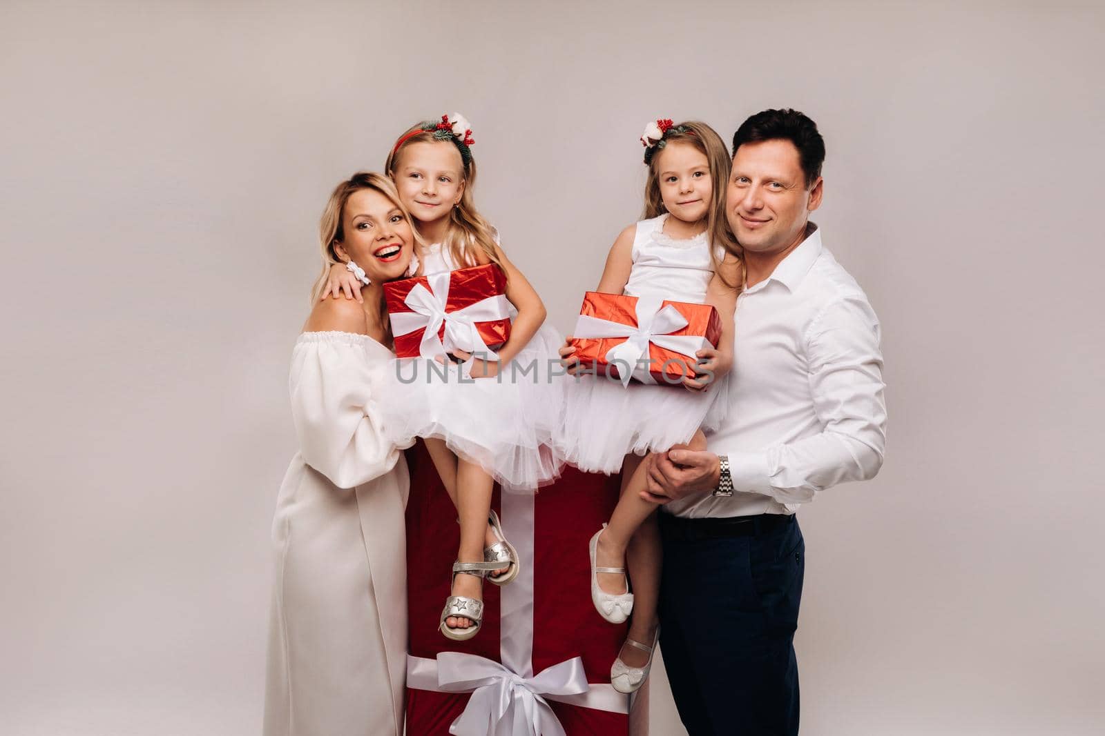 Portrait of a happy family with gifts in their hands on a beige background.