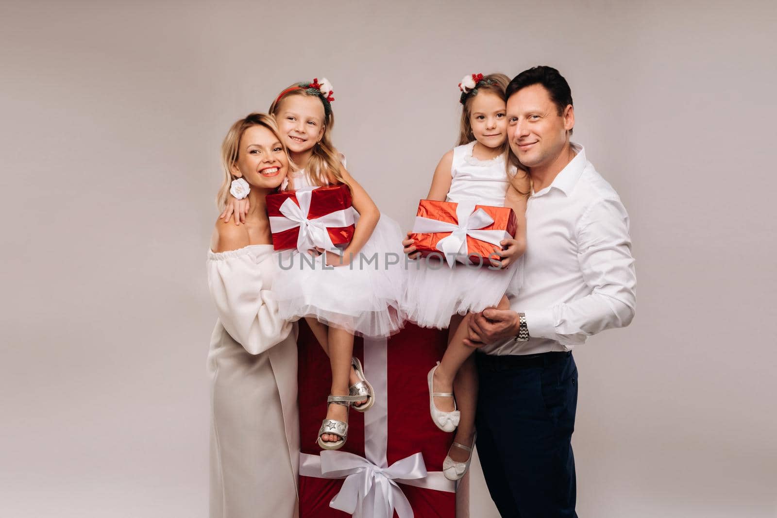 Portrait of a happy family with gifts in their hands on a beige background.