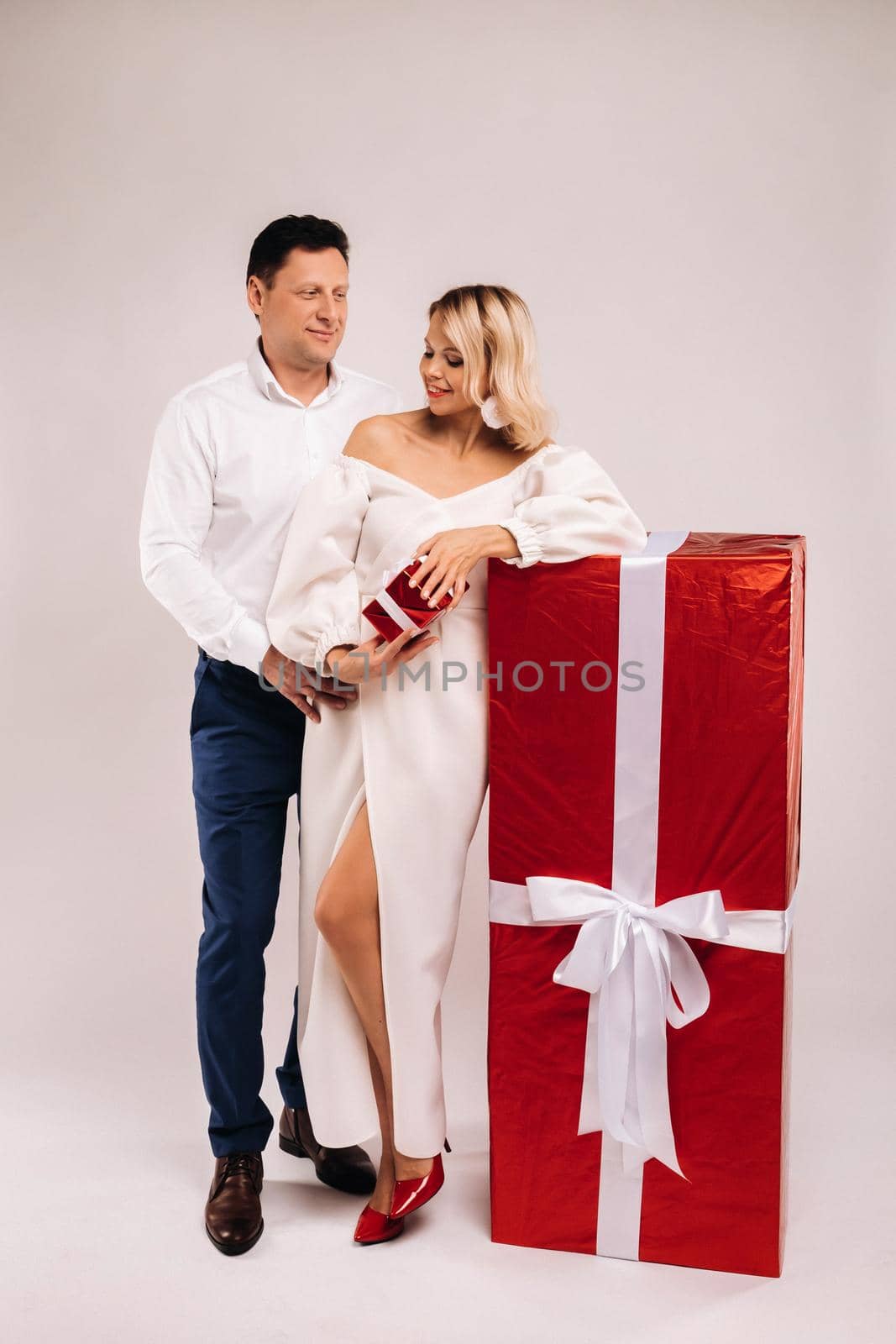 Portrait of a man and a woman with a large gift on a beige background by Lobachad