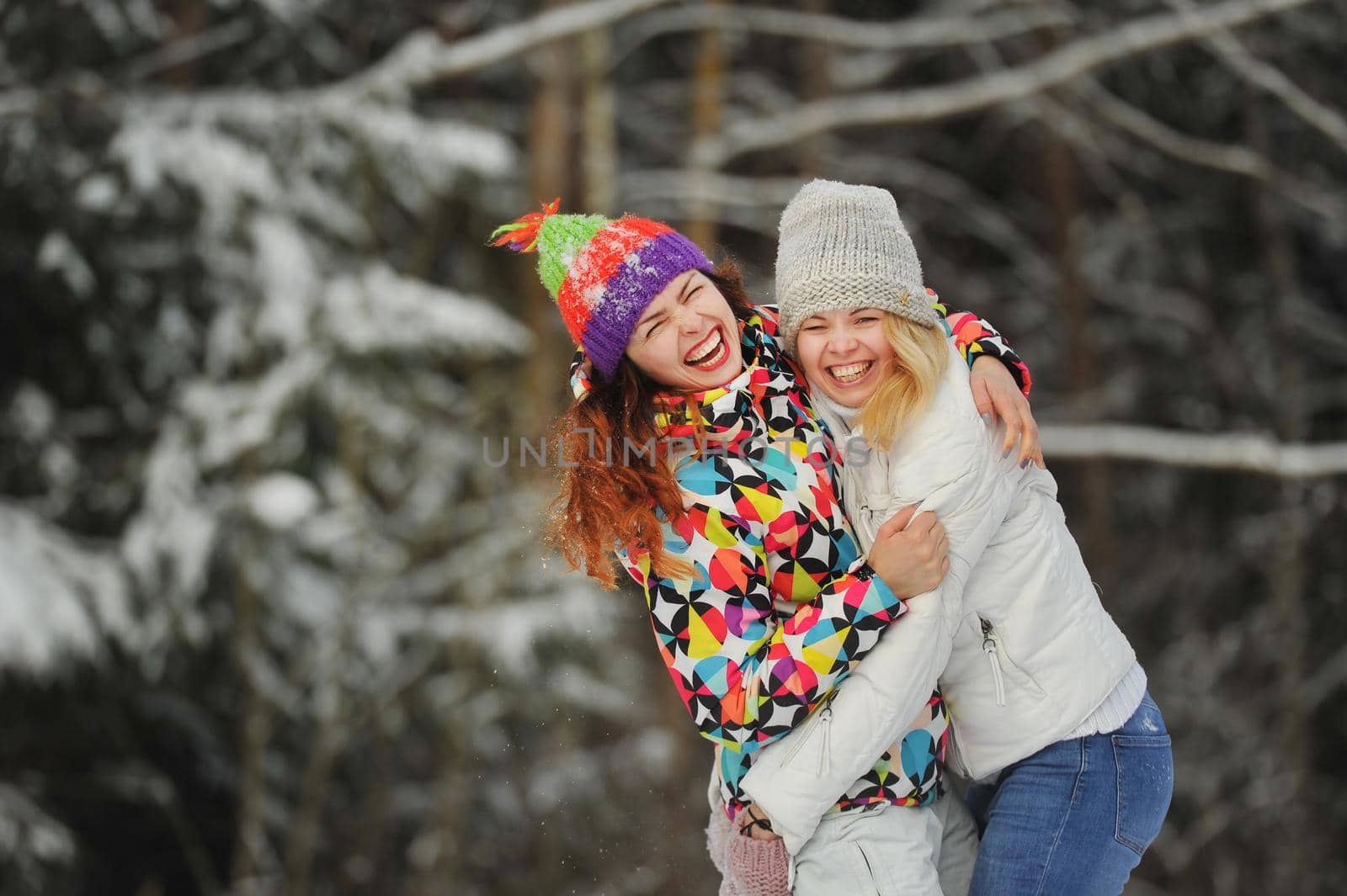 Two girls in the winter forest emotionally hug and smile.Happy women hug and Express joy.
