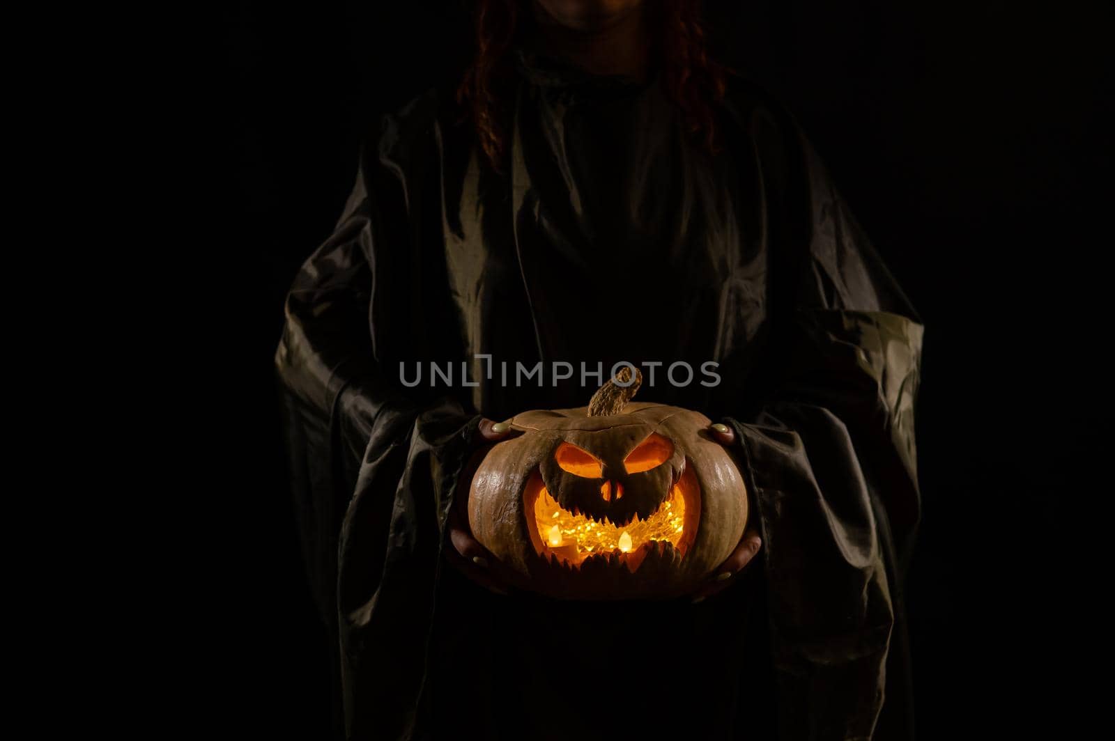 The witch is holding a pumpkin jack about a lantern glowing in the dark. Halloween