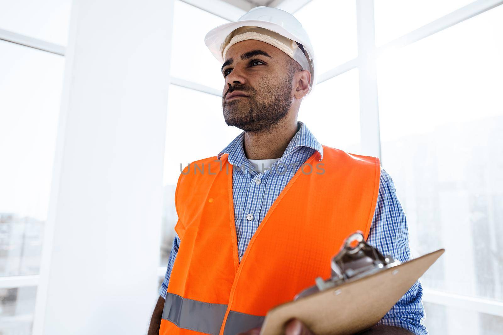 Foreman at work on construction site checking his notes on clipboard, close up