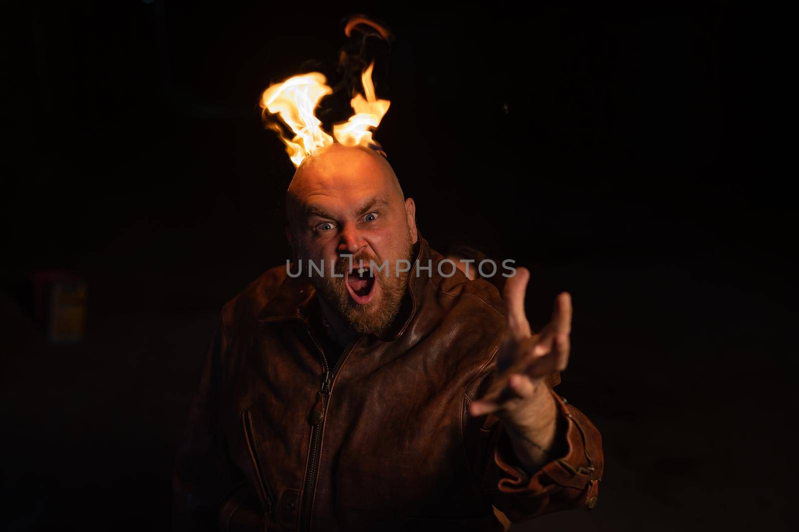 Bald man in a leather jacket with a burning head on a dark background. by mrwed54