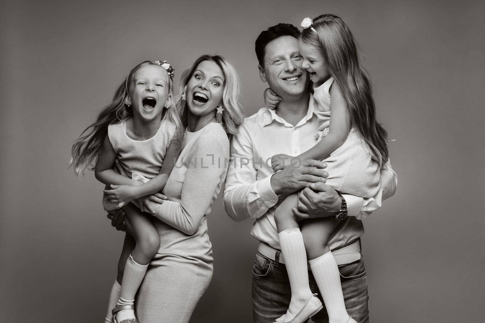 Happy parents hold their children in their arms and smile on a yellow background. an emotional family of four.