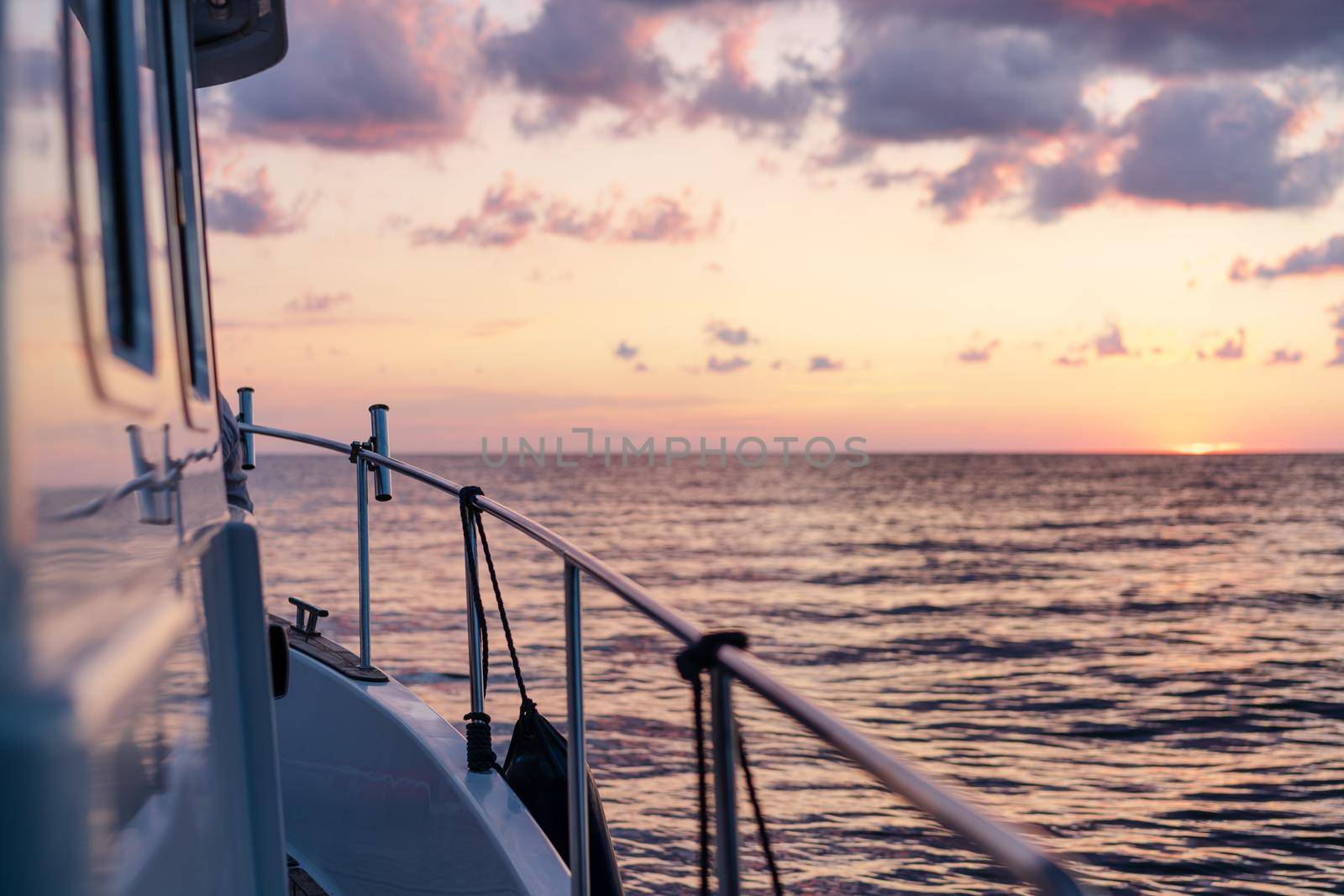 Deck of white yacht sailing in open sea at sunset, close up