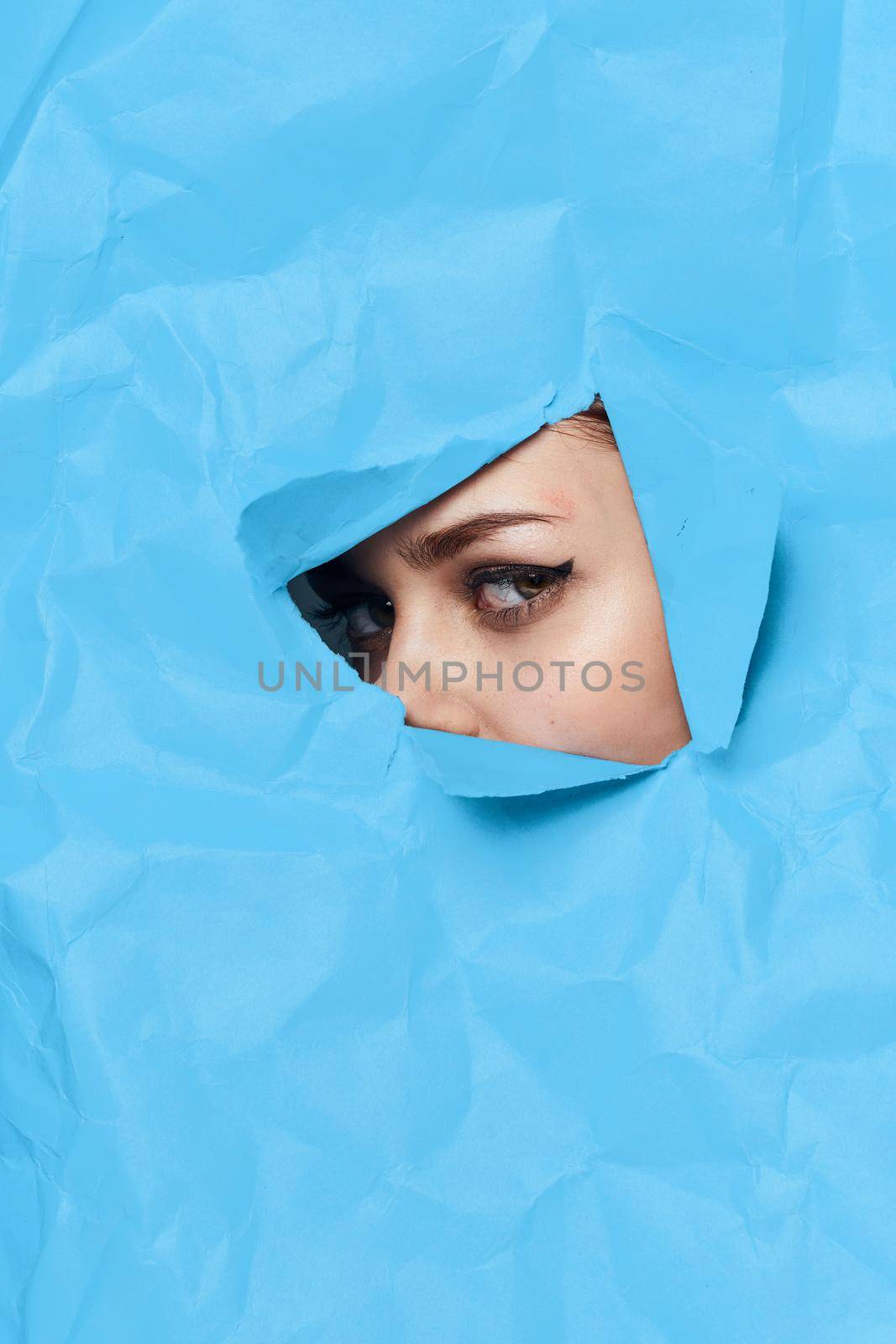 woman's face breaks through blue mockup close-up. High quality photo