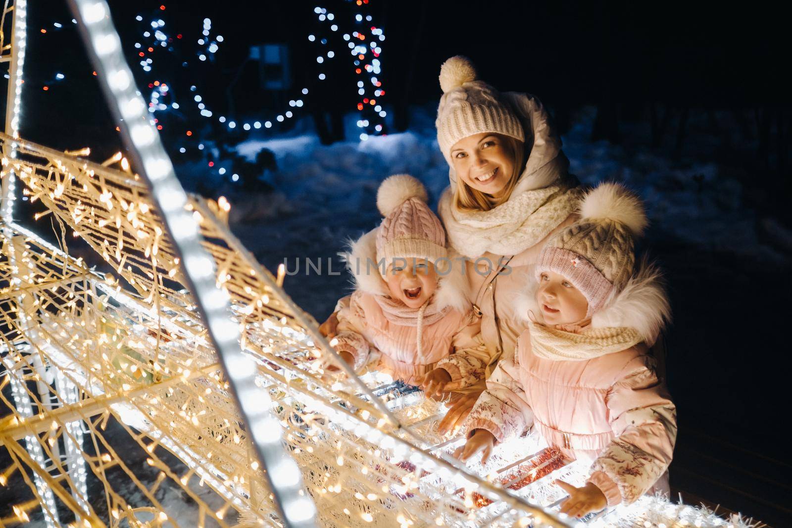 Mom and kids in the evening city with night Christmas lights by Lobachad