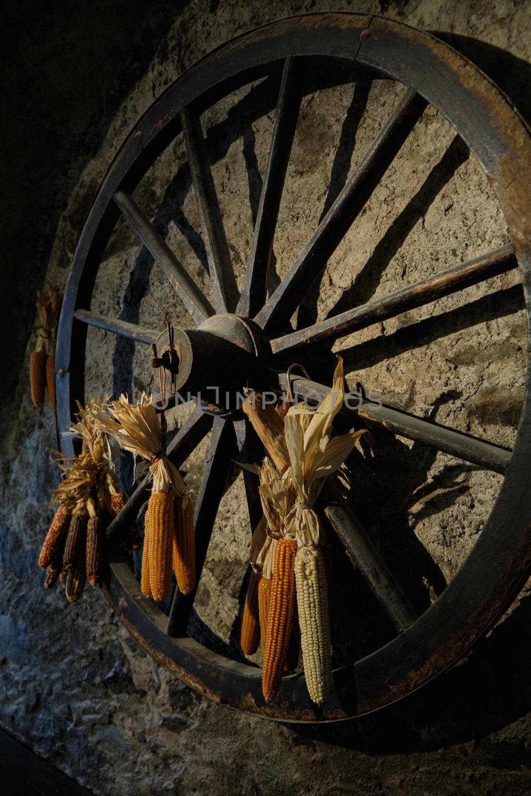 old wooden wagon wheel with corn decoration - Old mill in the small village of Breno - Brescia - Lombardy - Italy