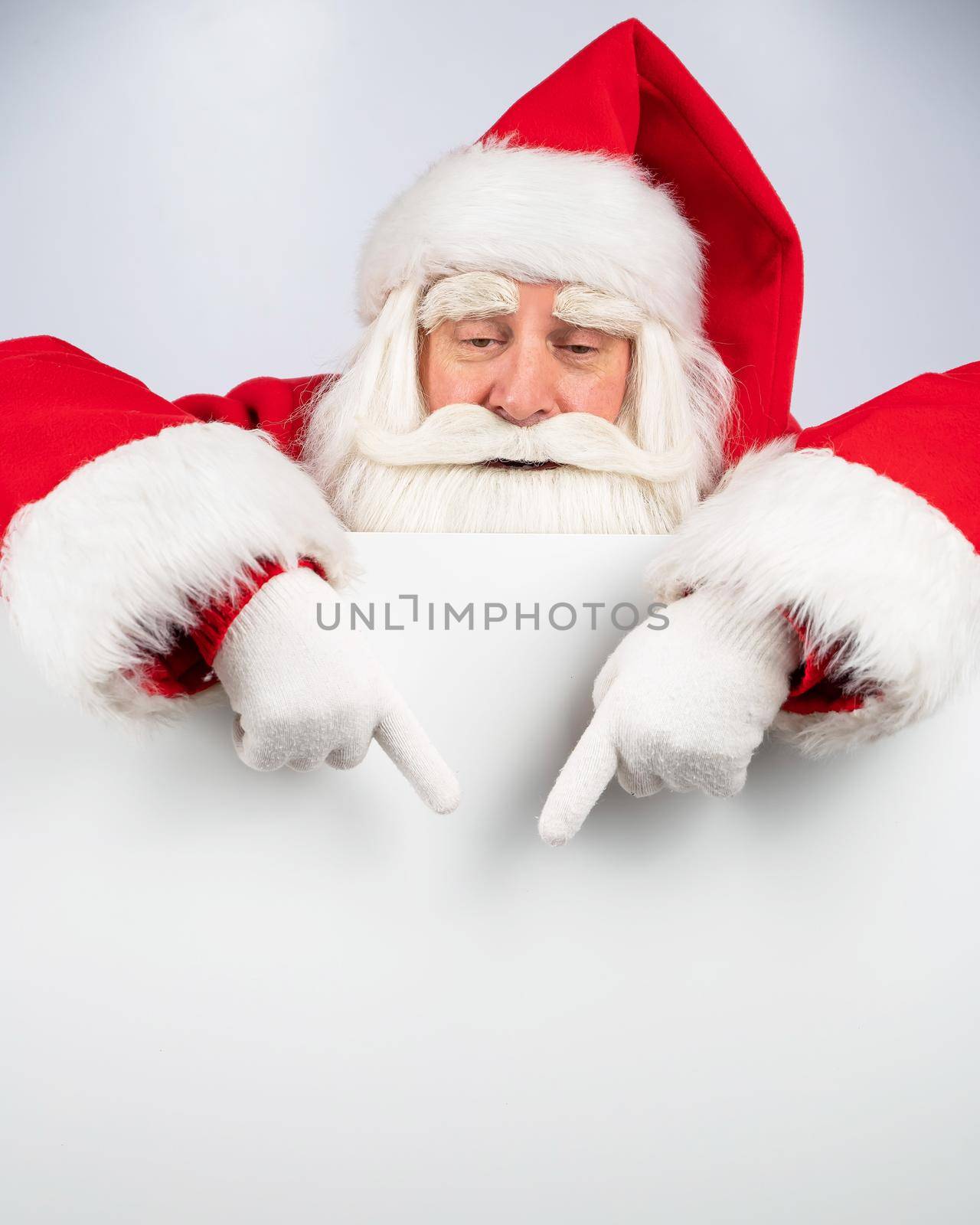 Santa Claus points to white copy space. Advertising. Merry Christmas