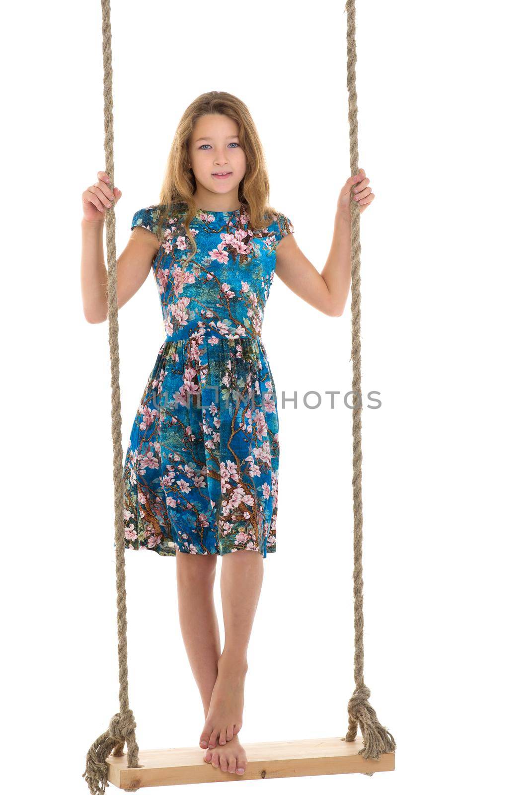 Girl standing on rope swing. Full length shot of long haired barefoot girl standing swinging on isolated white background. Portrait of happy preteen child