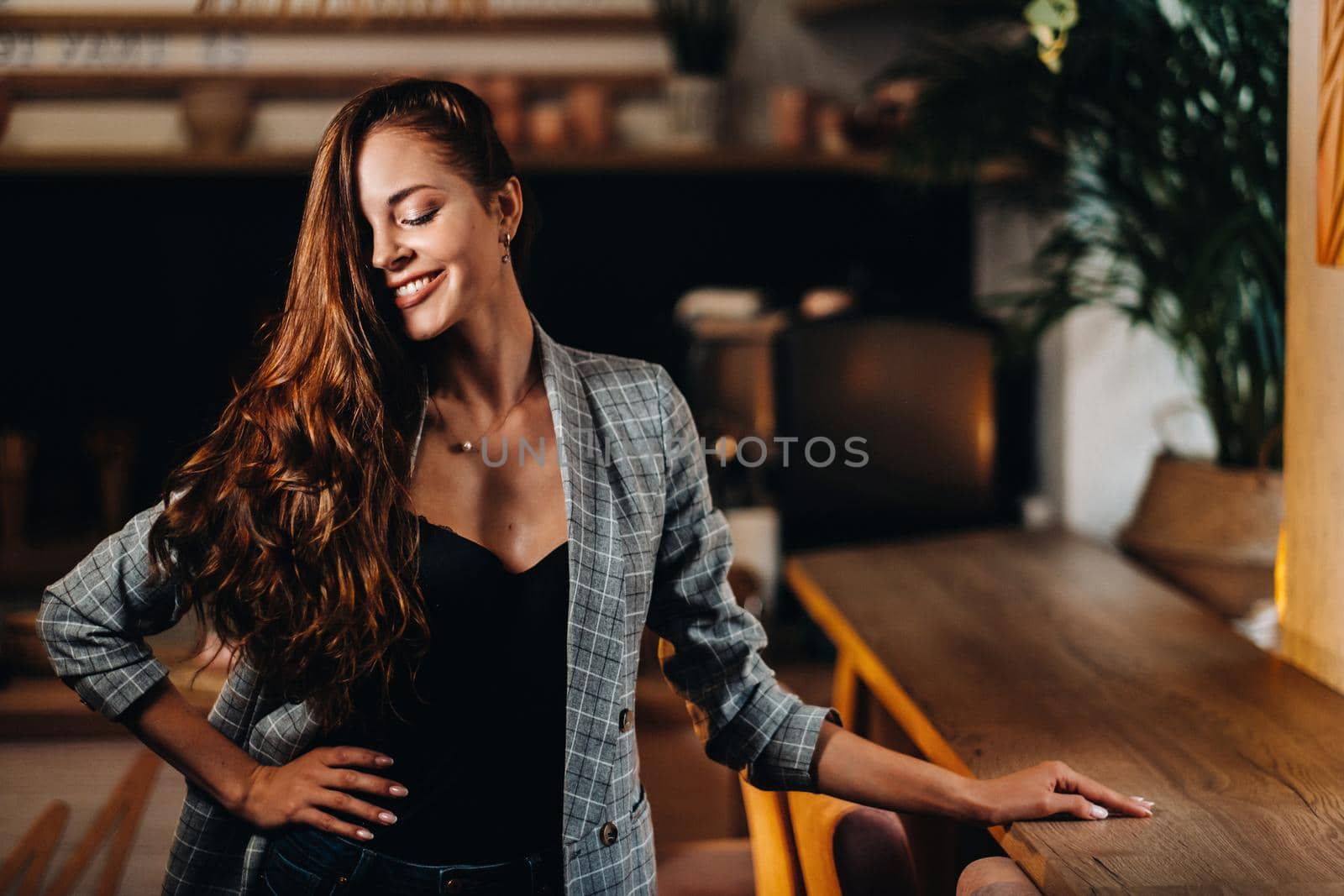 Portrait of a young European girl with long hair in a coffee shop in the evening light, a tall Girl in a jacket with long hair in a cafe by Lobachad