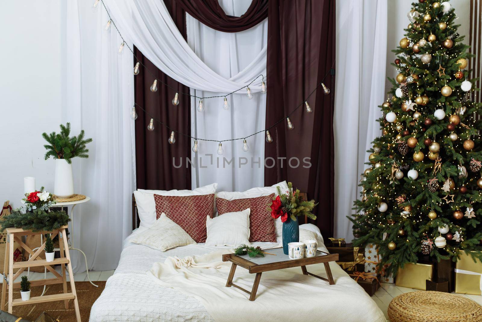 The interior of a modern bedroom is decorated for Christmas. Christmas tree in the apartment