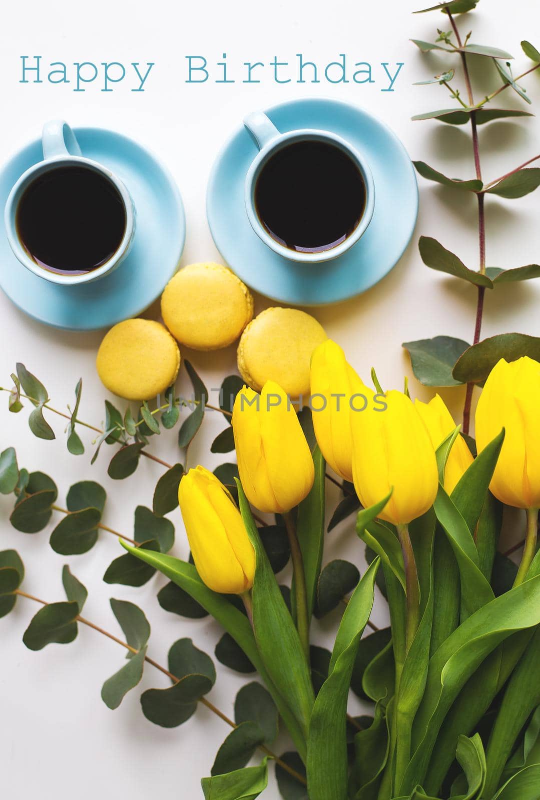 two blue cup of coffee with yellow tulips on an old table, the inscription happy birthday