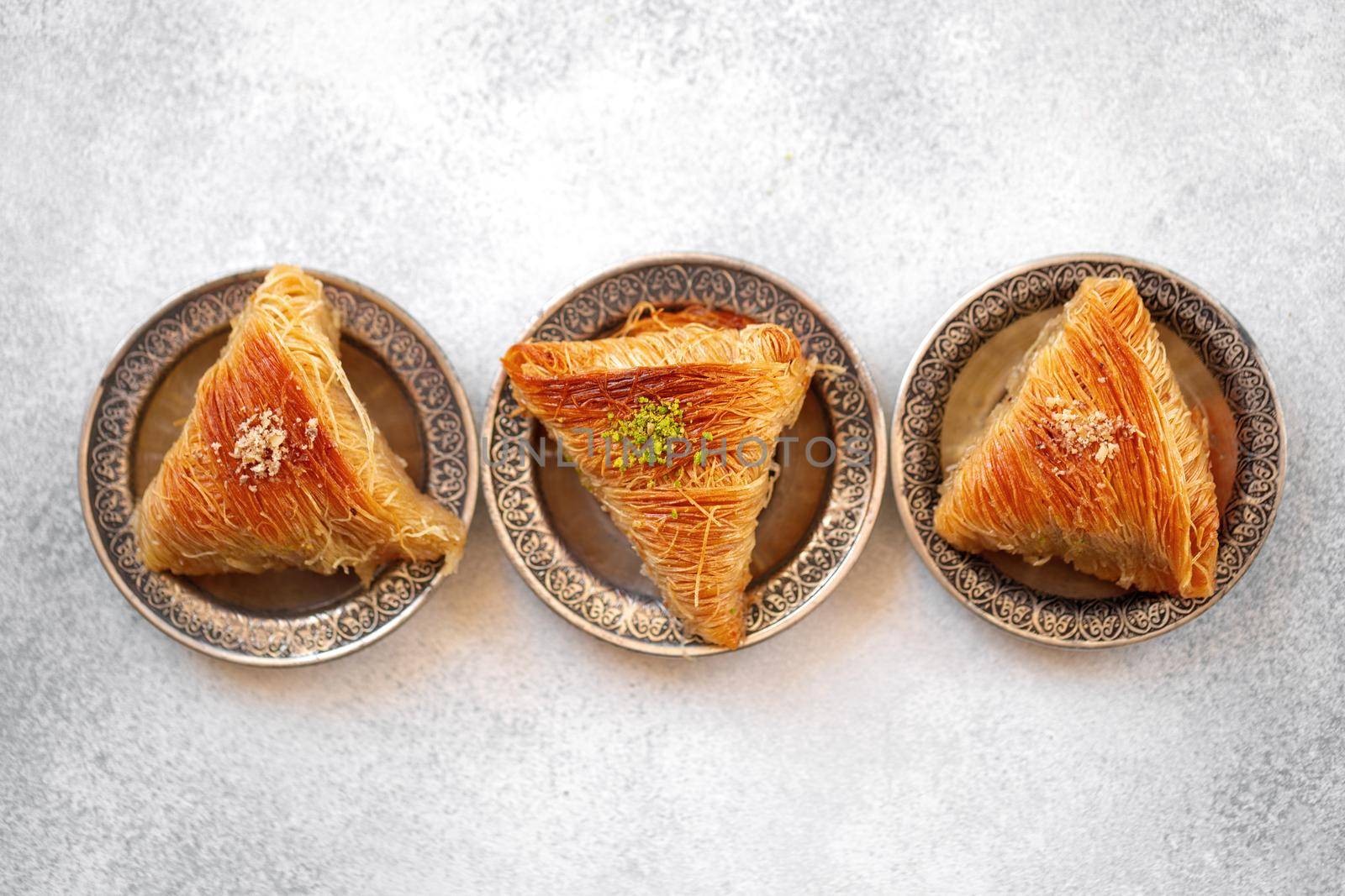 Turkish baklava on oriental metal plate on white table, close up