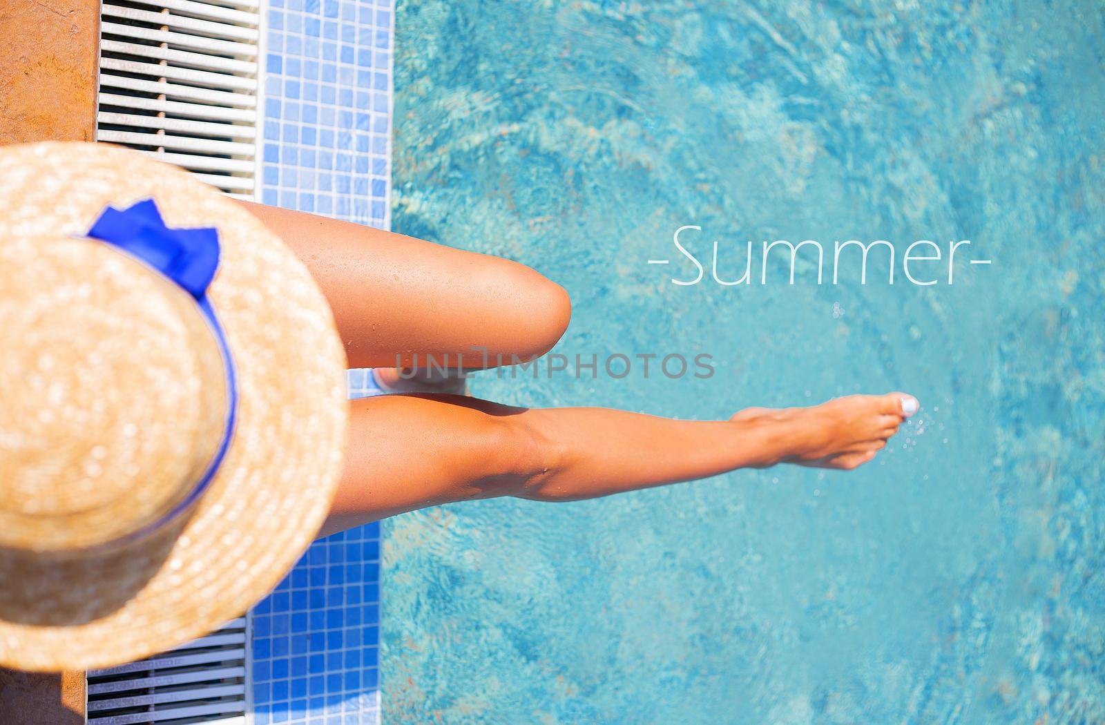 Beautiful girl in a hat near a blue pool - sun, summer, heat, summer inscription.