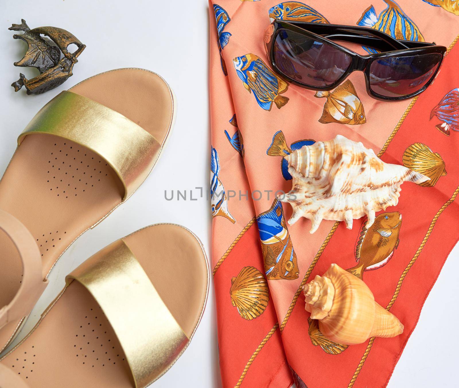 Beach concept: gilded women sandals, seashells, sunglasses