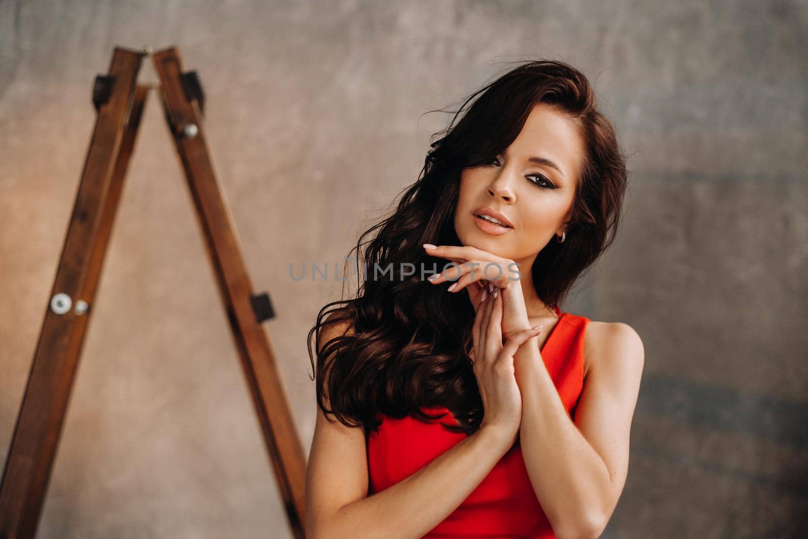 a brunette girl with long hair in a red dress poses in the studio.