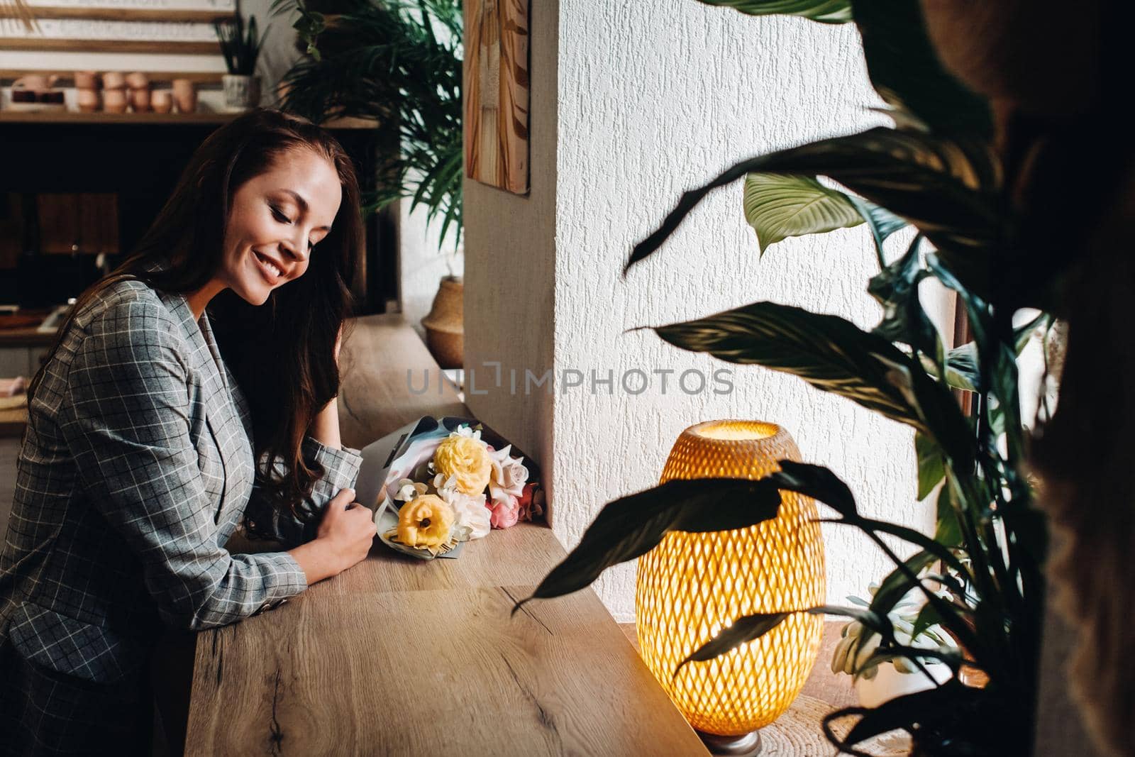 Portrait of a young European girl with long hair in a cafe with a bouquet standing near the window, a tall girl in a jacket with long hair in a cafe waiting by Lobachad