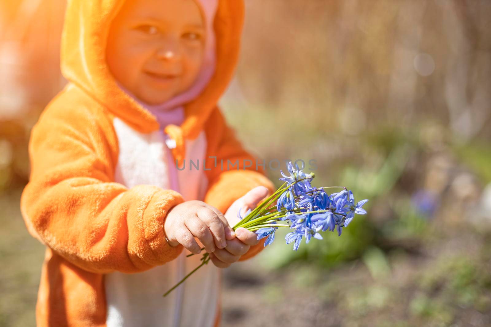 adorable toddler with spring flowers outdoors in sunlight