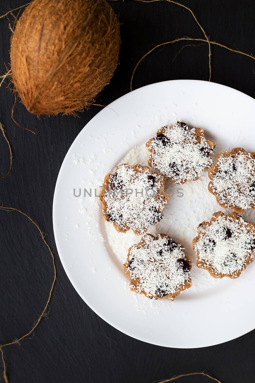 sweet coconut muffins on a white plate on a black board. by sfinks