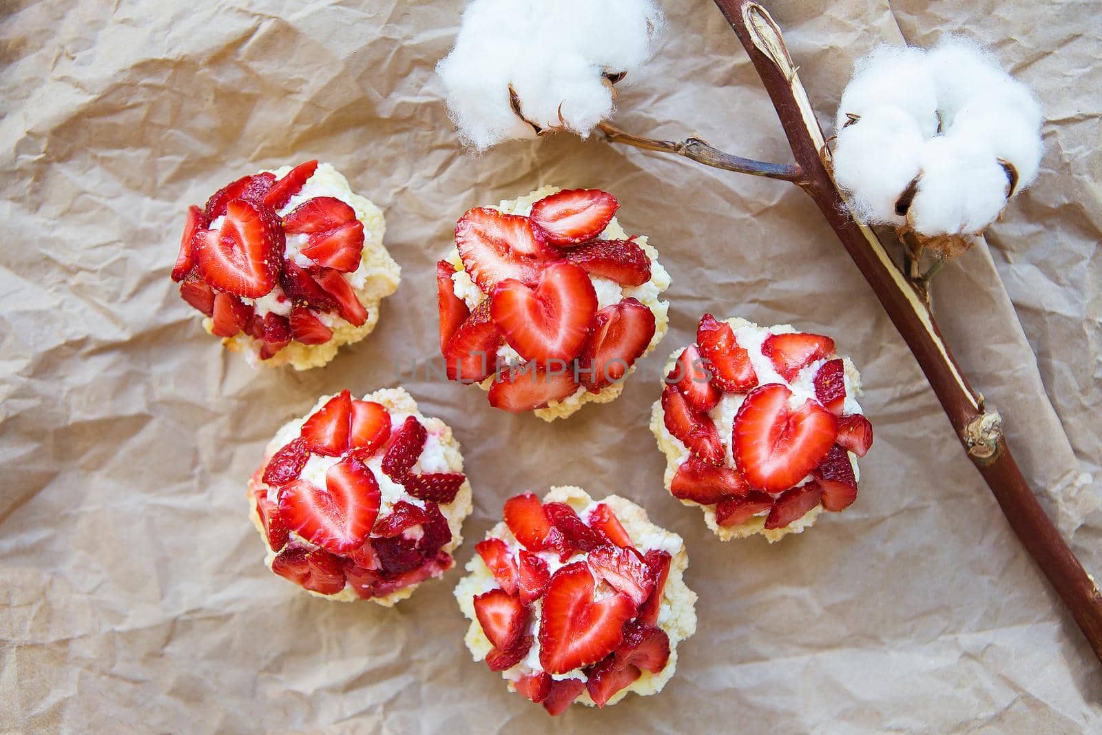 Very tasty muffins with fresh strawberries lie on kraft paper.