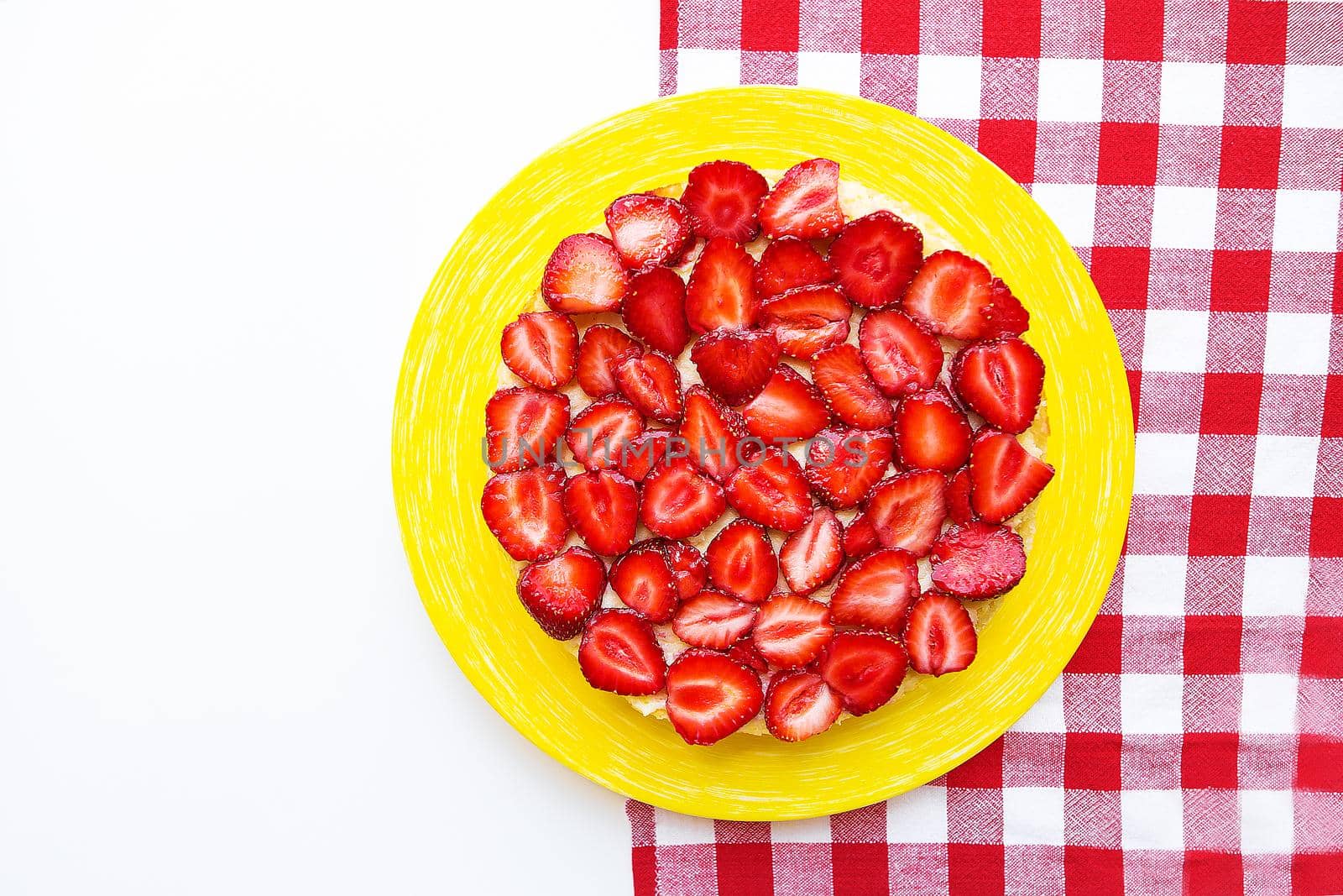 Bright and delicious strawberry cake on a red napkin in a cage.