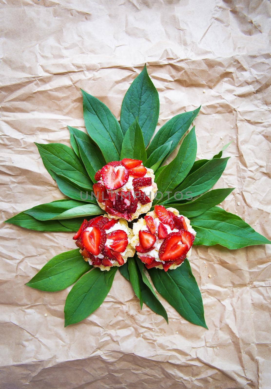 Beautiful and bright cupcakes with strawberries lie on green leaves by sfinks