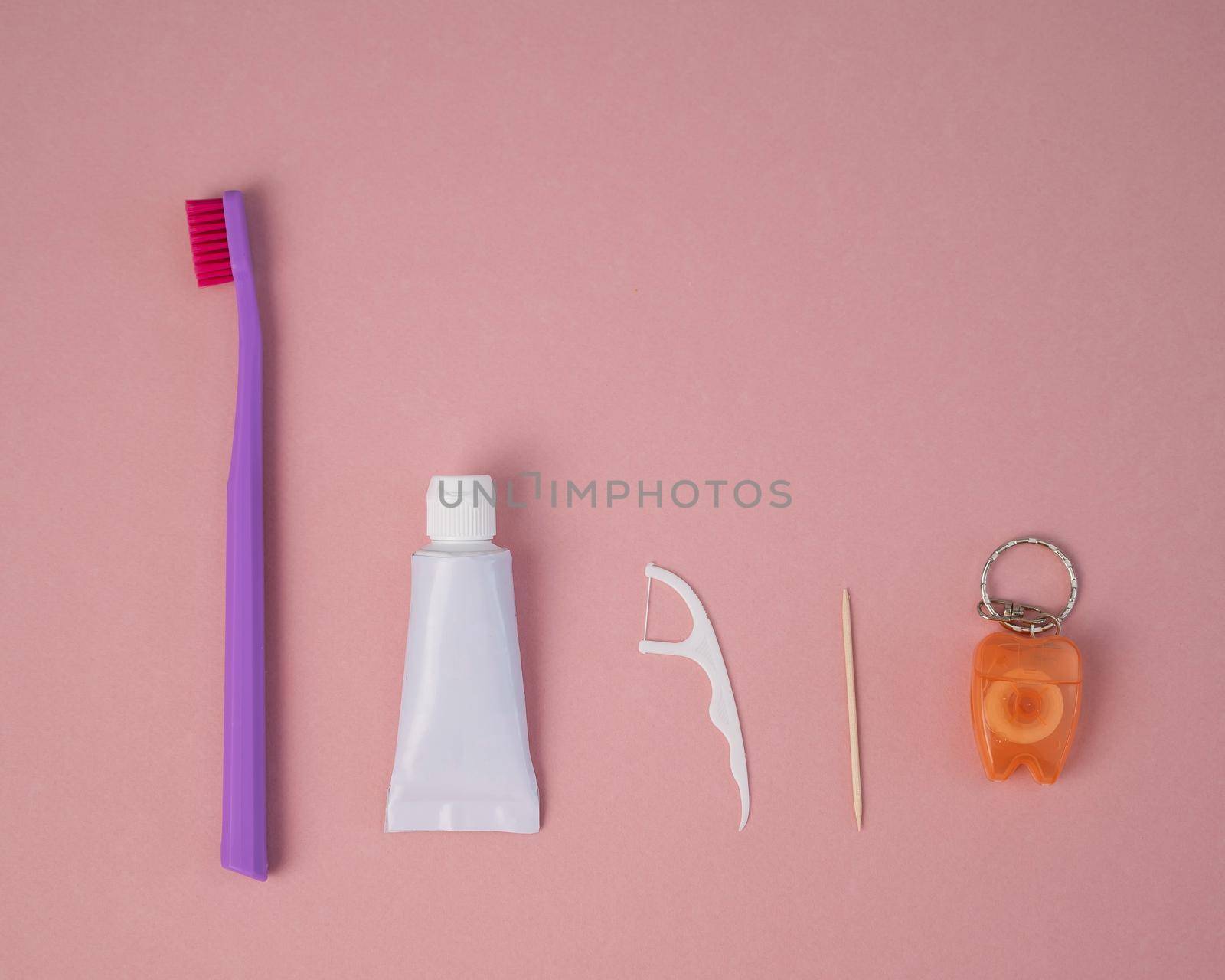 Oral hygiene products on a pink background. Toothbrush toothpaste dental floss and toothpick. Copy space