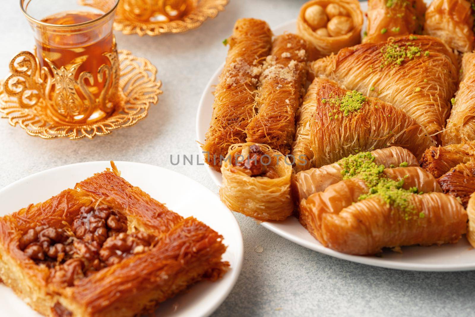 Various Turkish sweets and cup of tea on white textured background, close up