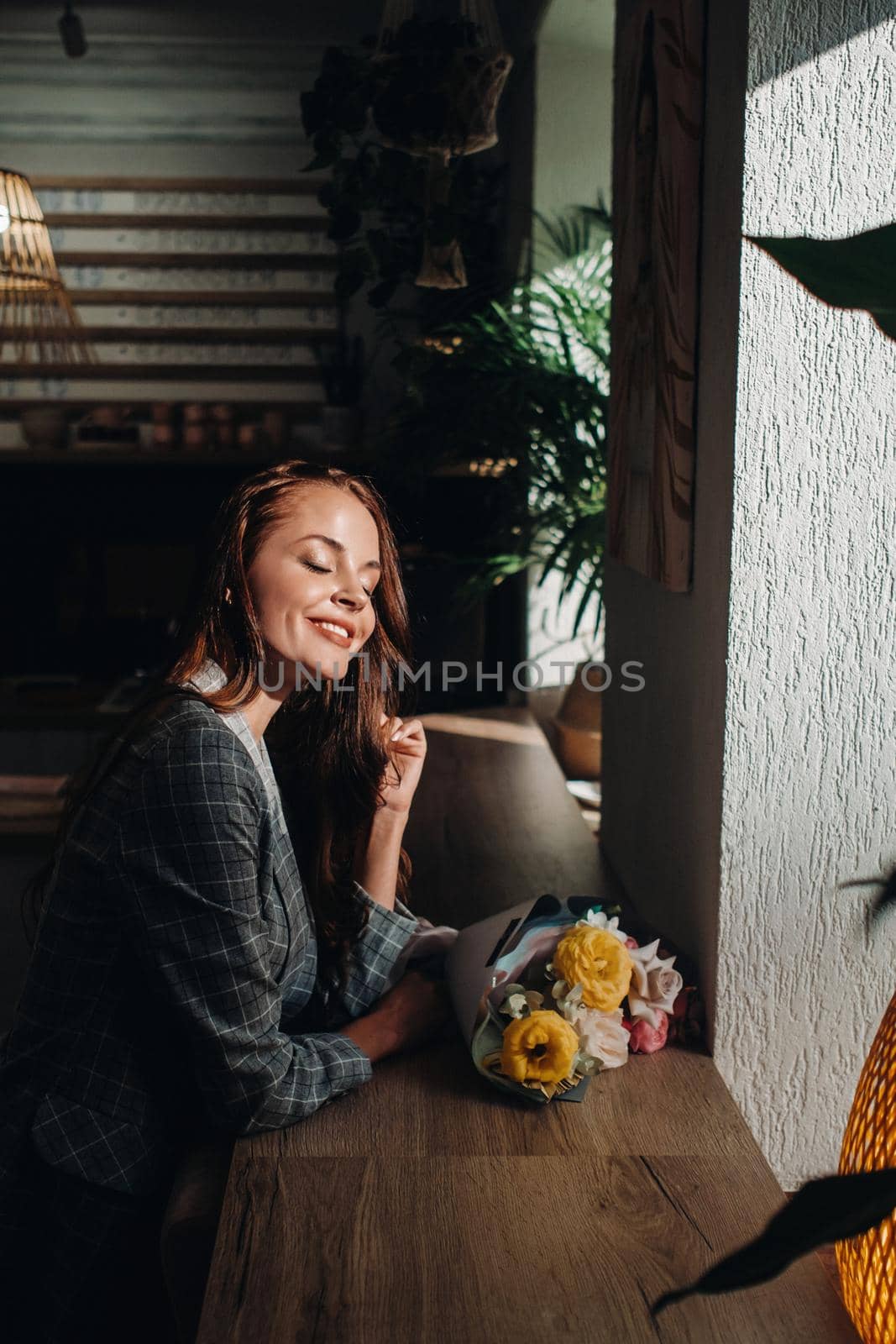 Portrait of a young European girl with long hair in a cafe with a bouquet standing near the window, a tall girl in a jacket with long hair in a cafe waiting by Lobachad