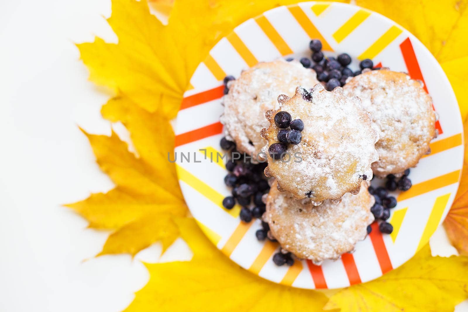 Blueberry muffins on plate and bright yellow fall foliage
