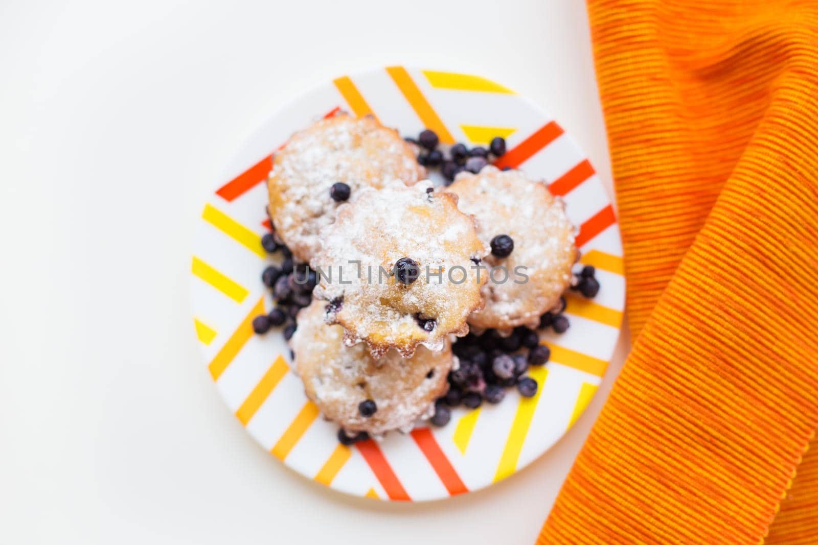 Blueberry muffins on a napkin and bright orange plate
