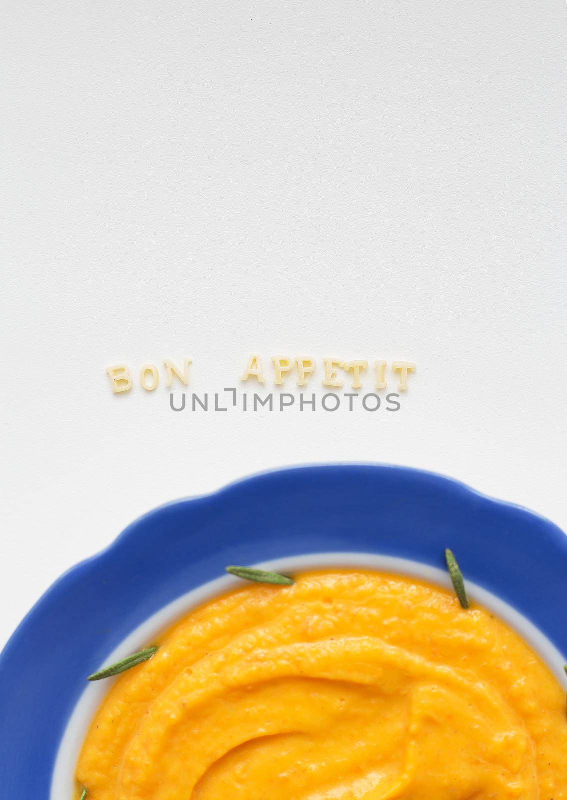 pumpkin soup in a blue plate on a napkin with flowers close-up