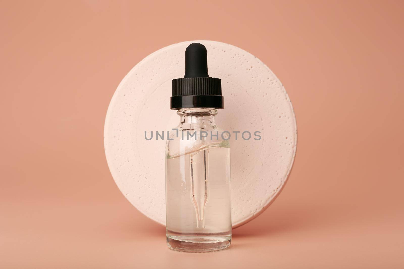 Still life with skin serum in dark bottle with round gypsum circle on dark beige background. Concept of anti aging or anti acne skin care and beauty treatment 