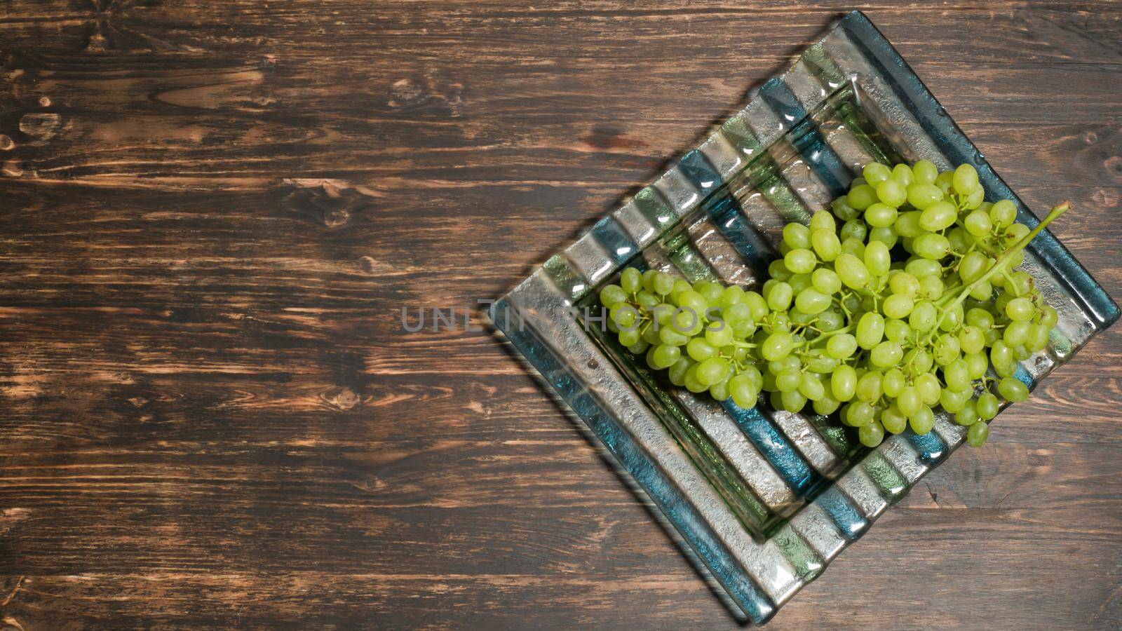 Bunch of grapes lying on a plate, top view by VadosLoginov