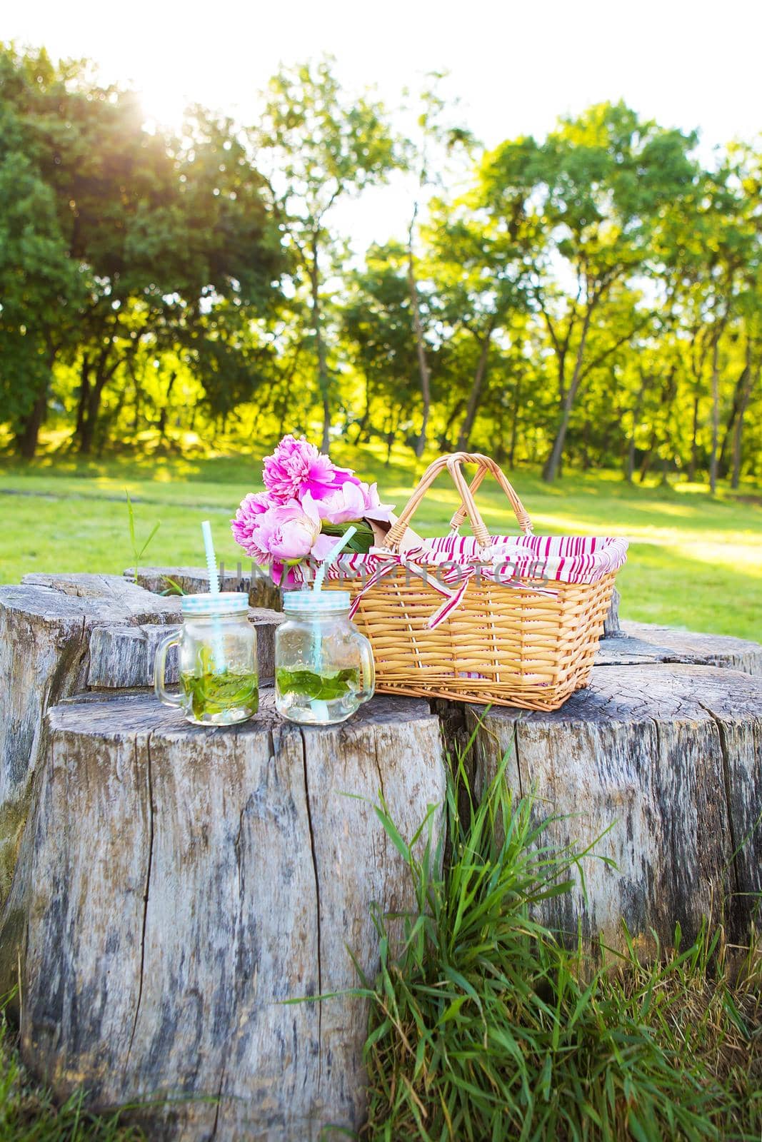 Straw basket with beautiful flowers and summer drinks-mojito