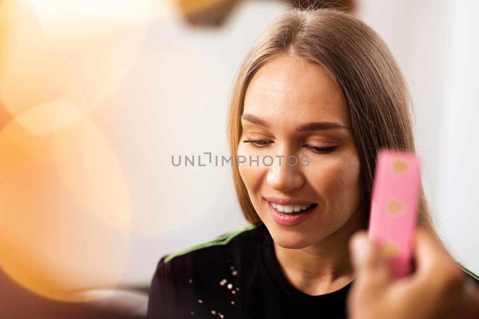 Surprised young woman opens a pink box with a present inside it