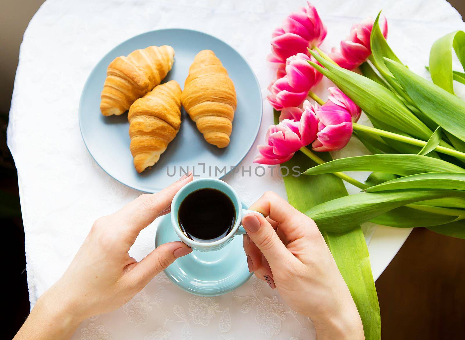 Girl with croissants and coffee, a bouquet of pink tulips, happy morning.