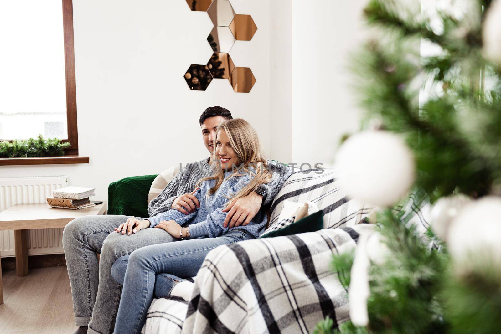 Sweet couple embracing on sofa at home during christmas holidays