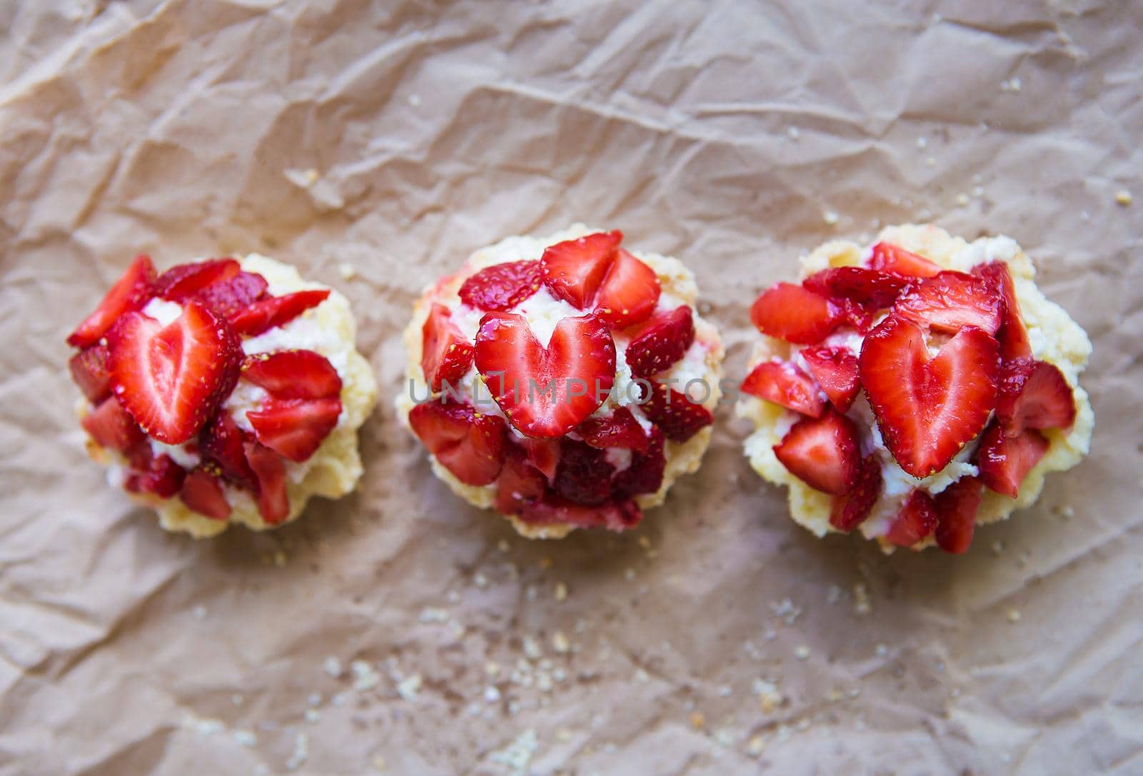 Very tasty muffins with fresh strawberries lie on kraft paper by sfinks